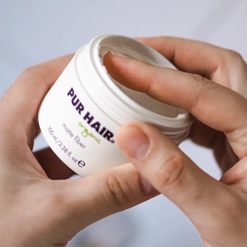 PUR HAIR Organic Matte Fiber 100 ml Dose, auf einem Tablett zwischen zwei kleinen Sukkulenten vor einem Fenster arrangiert