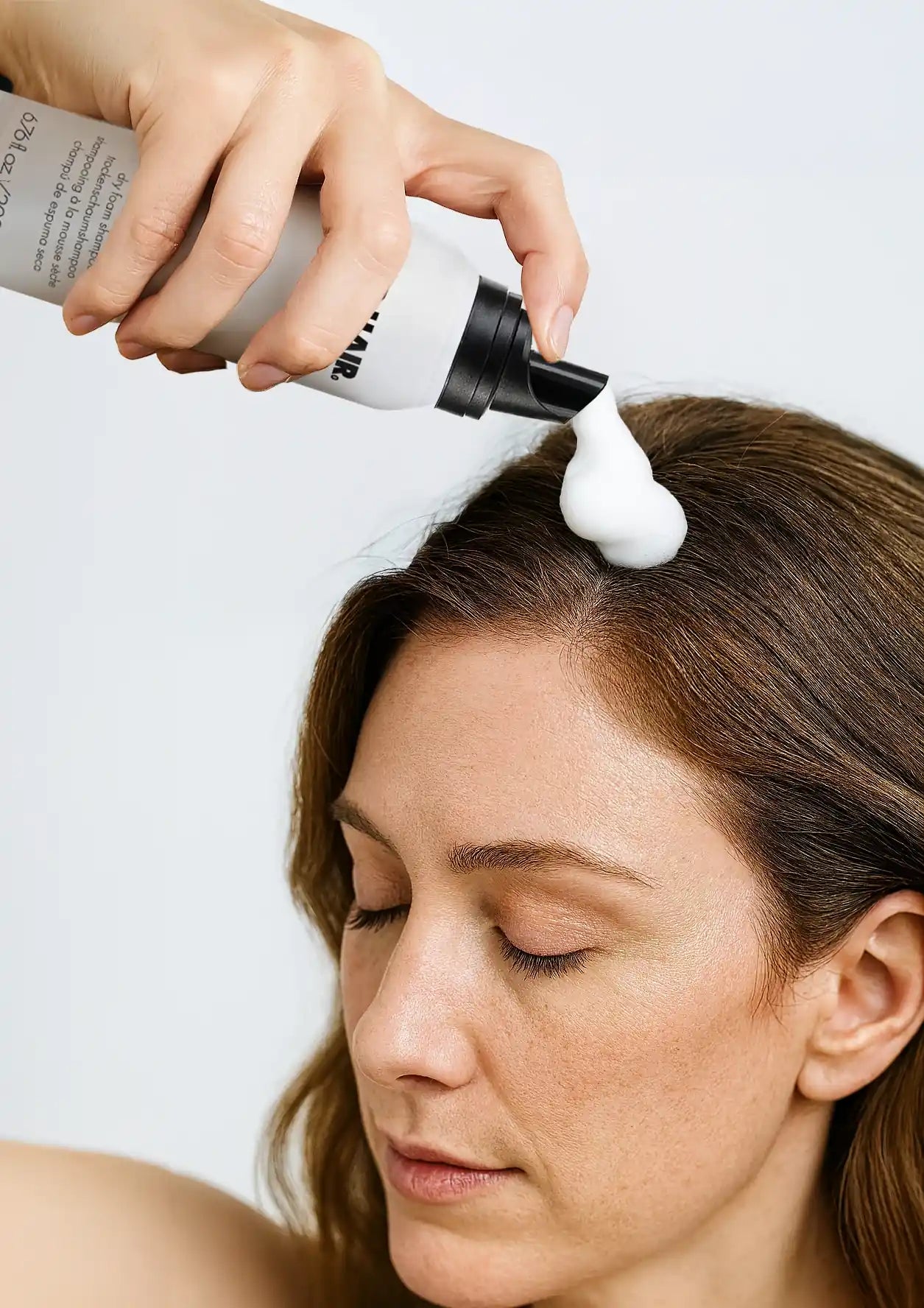 Frau trägt PUR HAIR Dry Foam Shampoo direkt am Haaransatz auf – sanfte Schaumformel für frisches Haar ohne Wasser