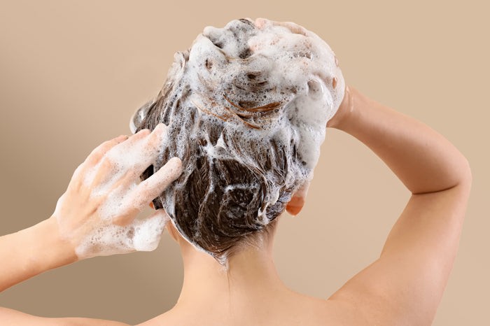 Frau schäumt sich die Haare mit Shampoo