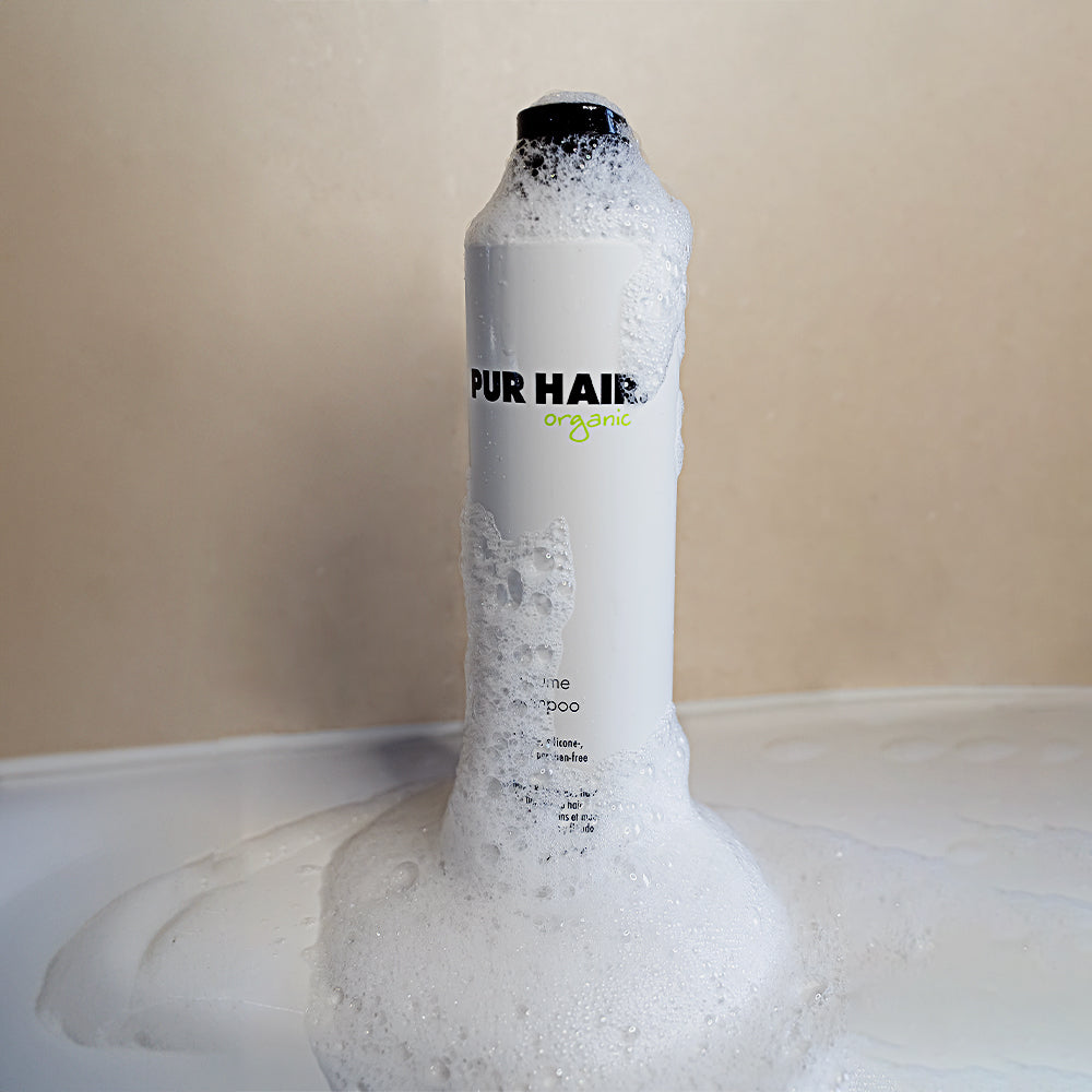 PUR HAIR Protein Shampoo vor beiger Wand umhüllt mit weißem Schaum
