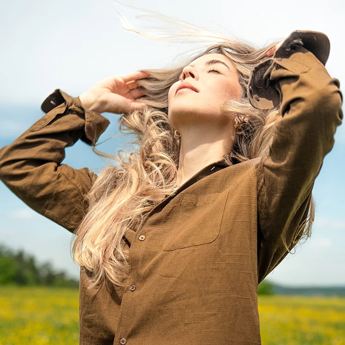 Frau mit langen blonden Haaren, Haare wehen im Wind, Frau schaut sinnlich nach oben, hält sich die Haare aus dem Gesicht