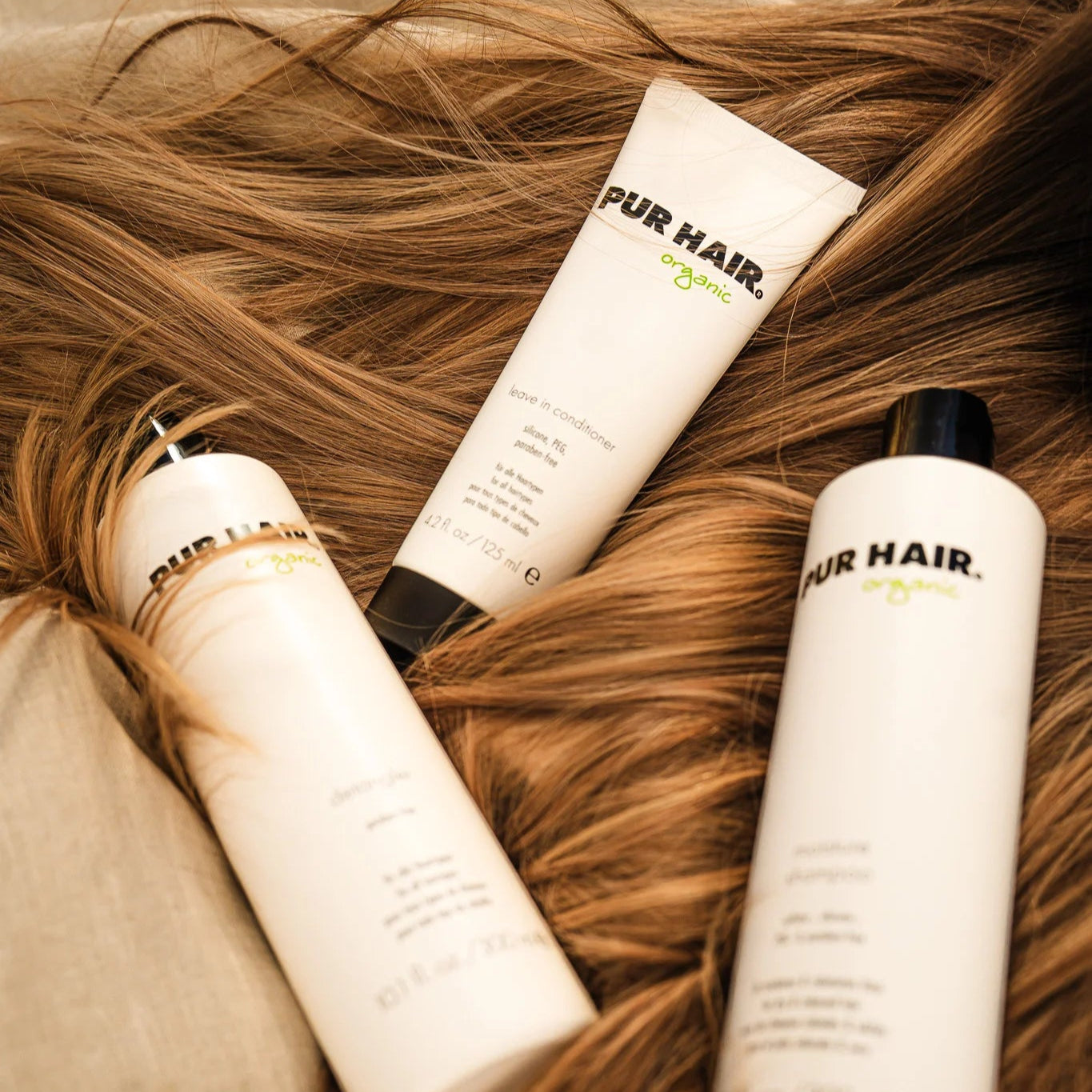 PUR HAIR Leave-In Conditioner, Detangler, Shampoo in 300 ml, liegen auf braunem Haar
