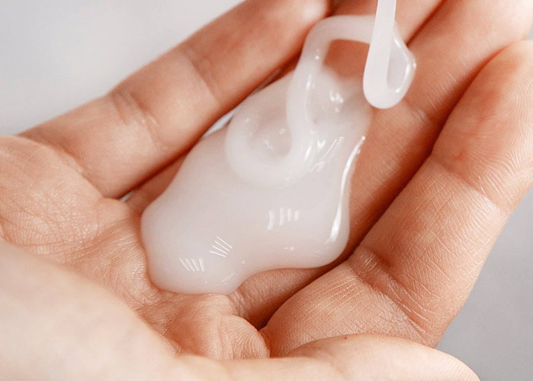 Nahaufnahme einer Handfläche mit frisch aufgetragenem Haarpflege-Produkt in cremiger Textur