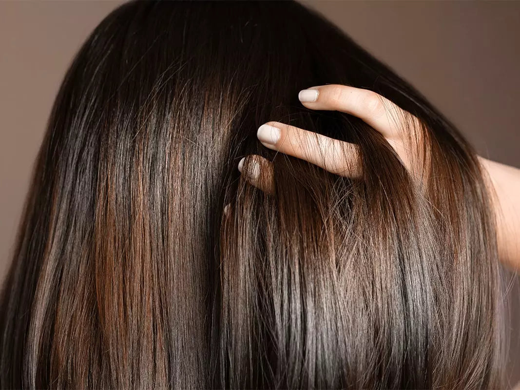 Nahaufnahme von glattem, dunkelbraunem Haar mit natürlichem Glanz – gepflegtes Haar, das sanft durch die Hand gestrichen wird