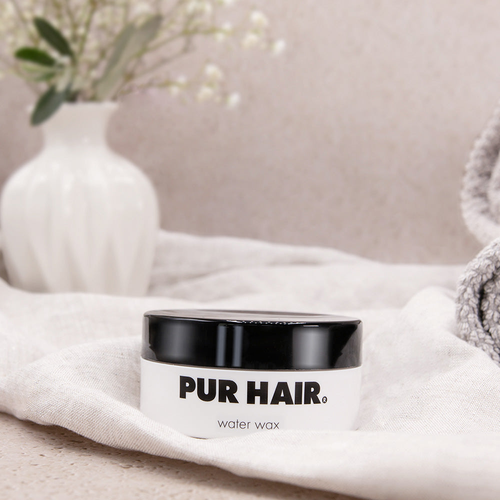 PUR HAIR Style Water Wax Haarstyling-Wachs, 100 ml, dekorativ inszeniert mit Handtuch, Vase und Pflanzen für natürliche Pflege und Styling im Bad