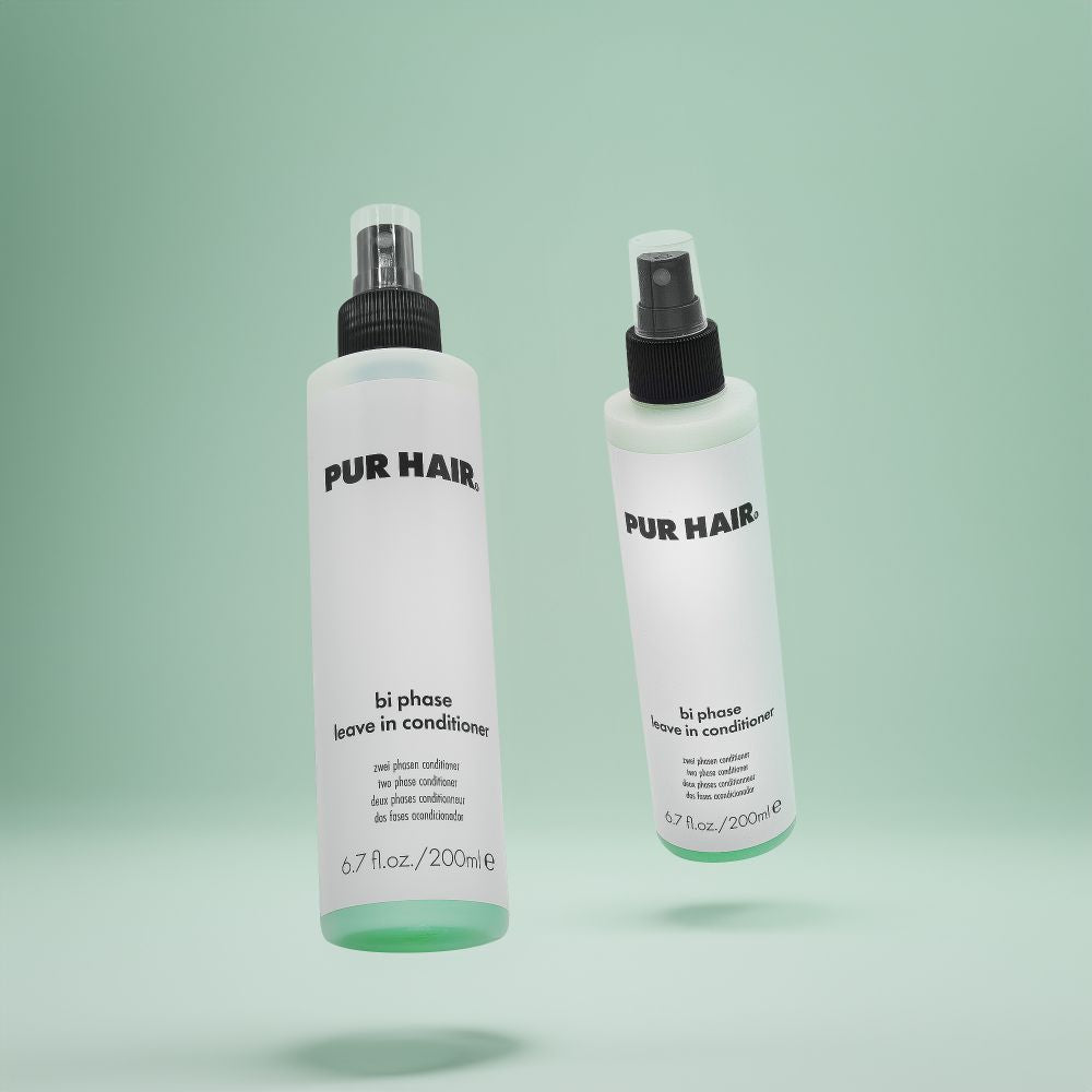Zwei Flaschen PUR HAIR Bi Phase Leave-in Conditioner, 200 ml, mit Sprühkopf vor grünem Hintergrund