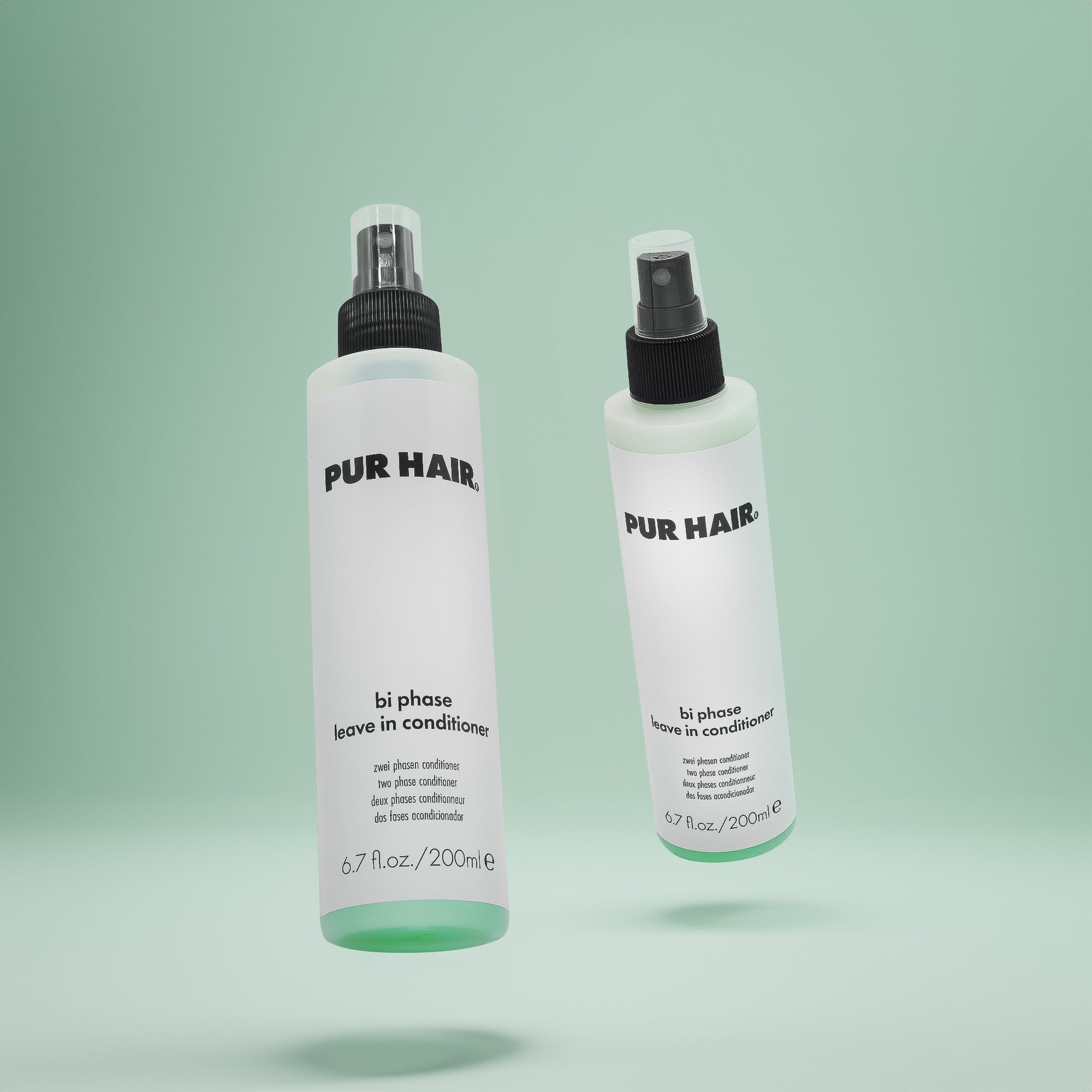 Zwei Flaschen PUR HAIR Bi Phase Leave-in Conditioner, 200 ml, mit Sprühkopf vor grünem Hintergrund