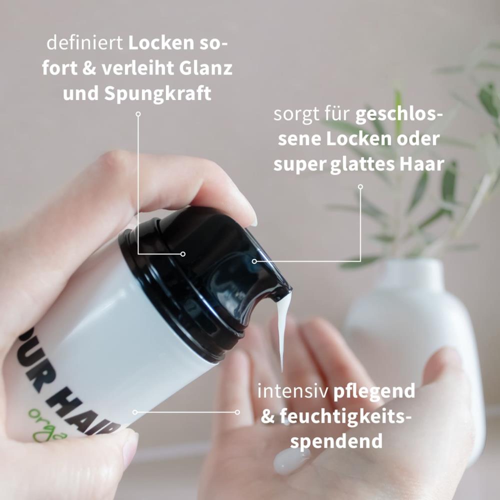 Hand gibt PUR HAIR organic Blow Out Cream in die Handfläche – Styling-Creme definiert Locken, sorgt für Glanz oder glattes Haar und spendet intensive Feuchtigkeit