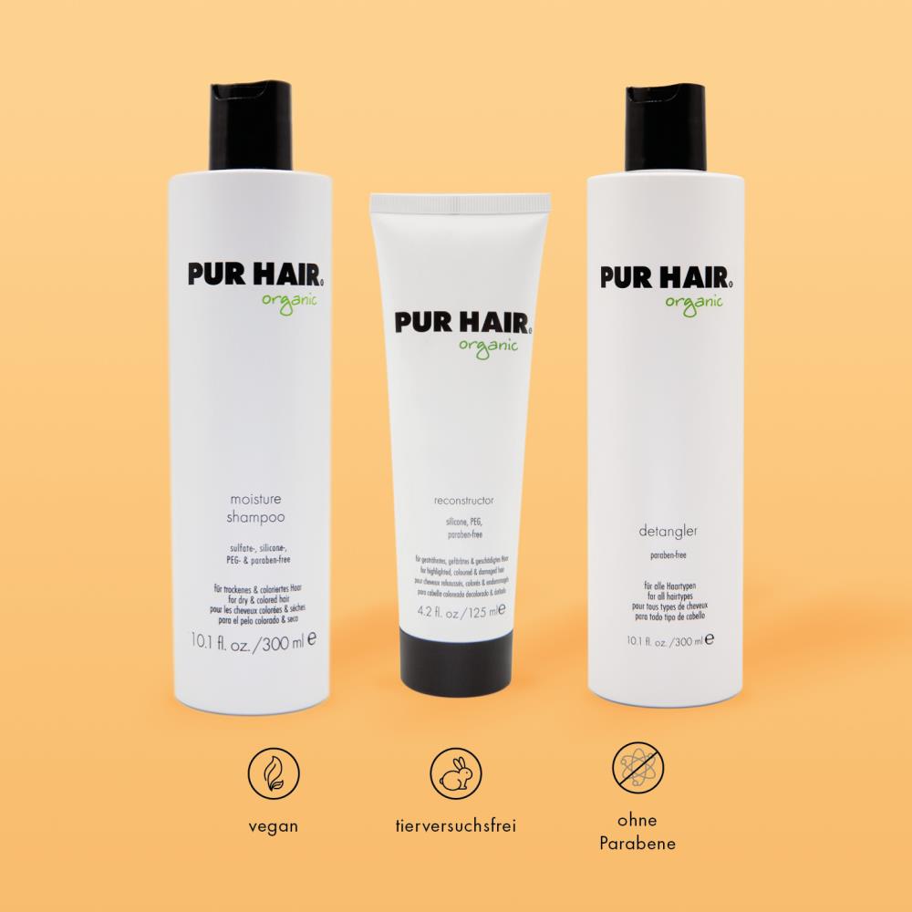 PUR HAIR Organic Haarpflege-Set: Moisture Shampoo, Reconstructor und Detangler vor orangenem Hintergrund. Symbole für vegan, tierversuchsfrei und ohne Parabene