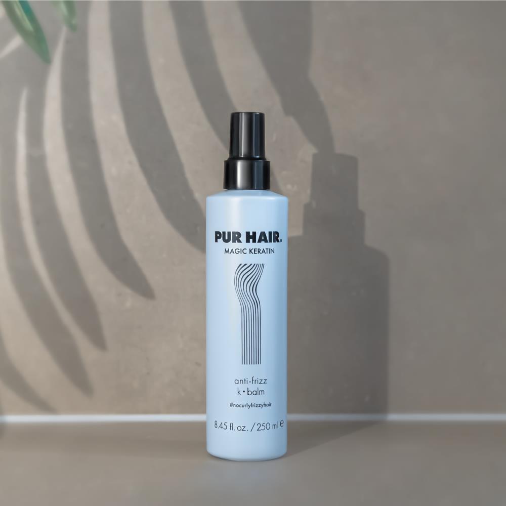 PUR HAIR Magic Keratin Balm Spray, 250 ml Flasche in hellblau mit schwarzem Deckel, dekorativ vor Steinwand platziert