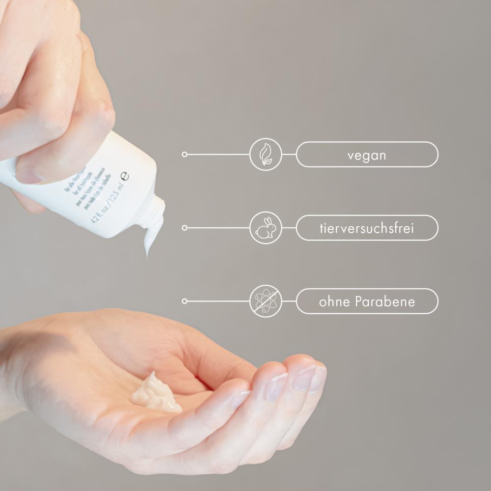 Finger drückt weißes Magic Treatment aus der Tube in die Handfläche, daneben Symbole: vegan, tierversuchsfrei, ohne Parabene