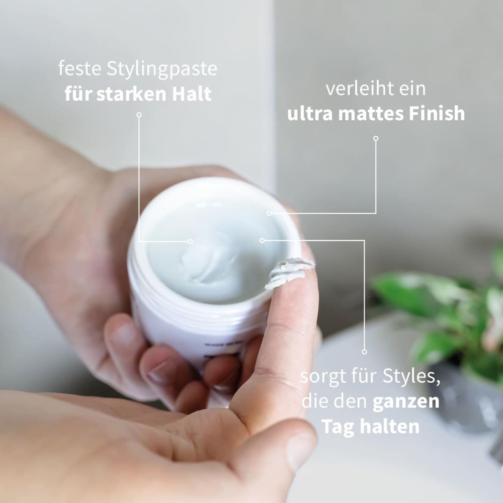 PUR HAIR Stylingpaste in offener Dose, Finger entnimmt Produkt. Beschriftung: feste Stylingpaste für starken Halt, verleiht ein ultra mattes Finish, sorgt für Styles, die den ganzen Tag halten