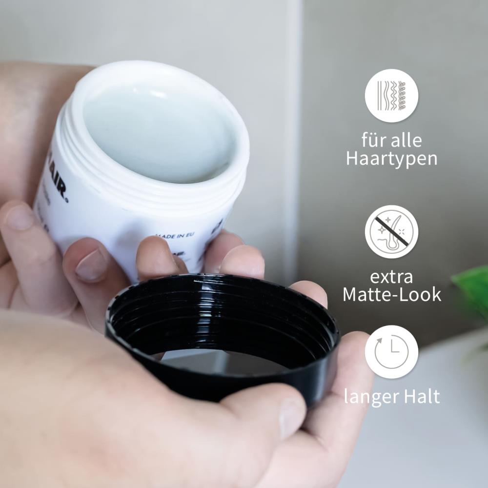 PUR HAIR Styling-Paste in offener Dose, gehalten in zwei Händen. Eigenschaften: für alle Haartypen geeignet, extra Matte-Look, langer Halt