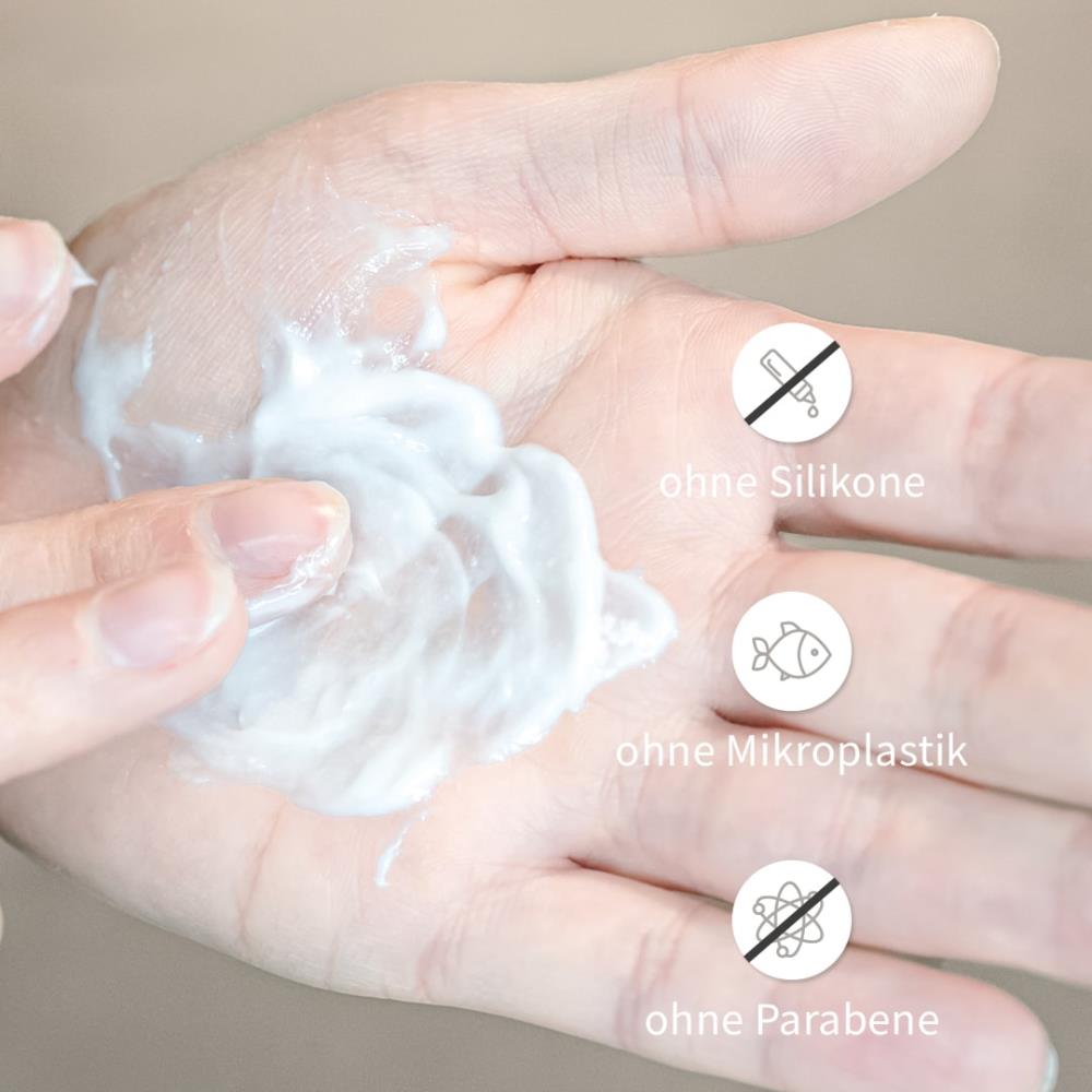 Finger verreibt cremige Textur vom Reconstructor auf der Hand, daneben Symbole: ohne Silikone, ohne Mikroplastik, ohne Parabene