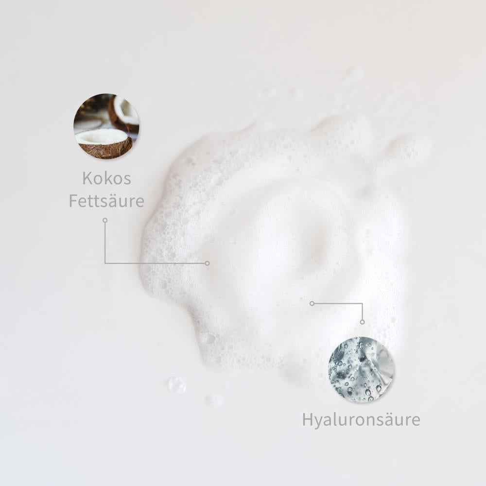 Weiße Schaum-Textur mit markierten Inhaltsstoffen: Kokosfettsäure, Hyaluronsäure
