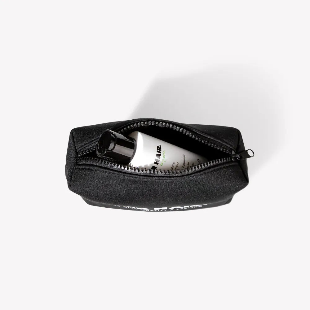 PUR HAIR Travel Bag, in schwarz, mit weißer 100 ml Flasche, auf weißem Hintergrund
