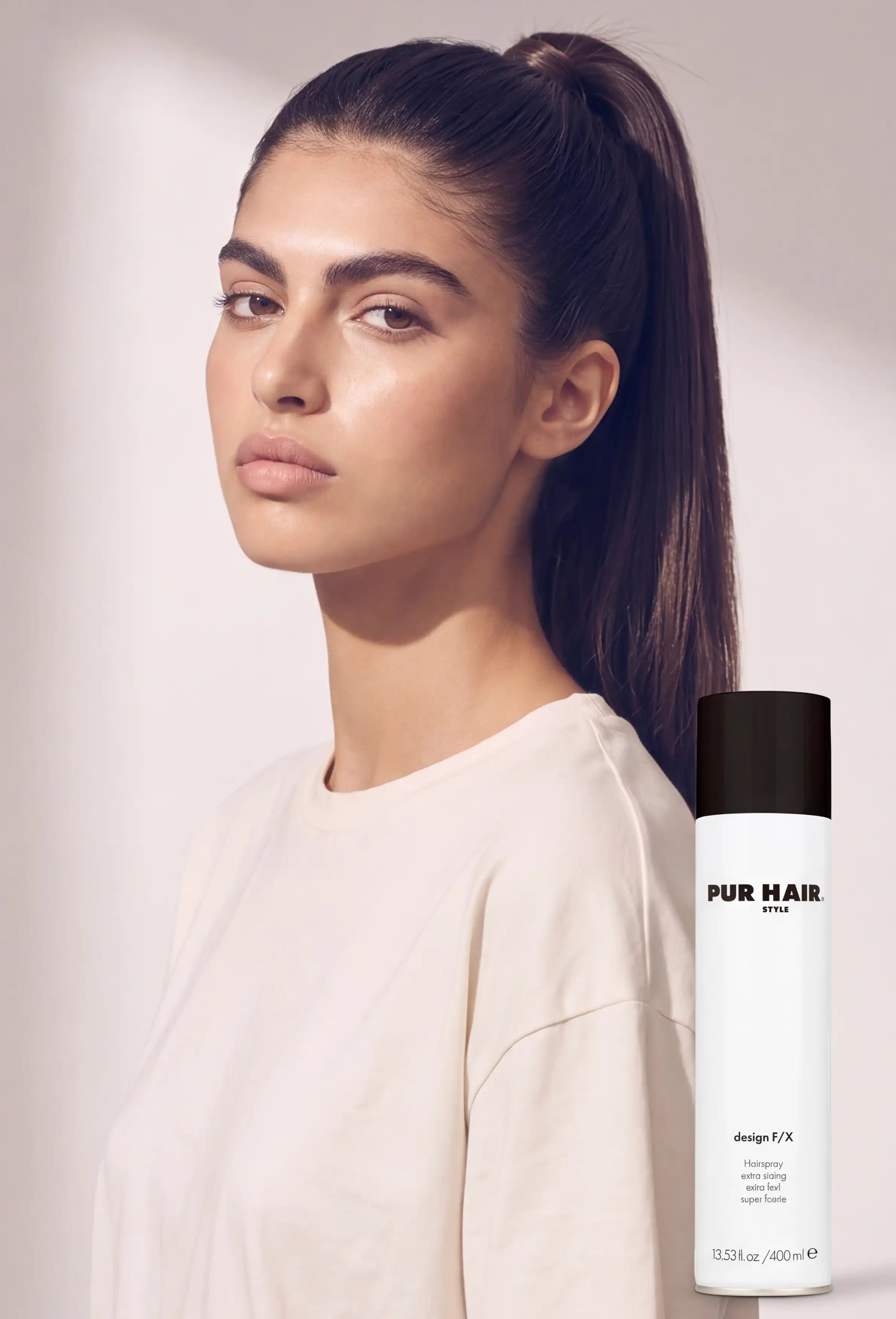 Model mit glattem hohen Pferdeschwanz neben PUR HAIR Design F/X Haarspray für starken Halt beim Haarstyling.