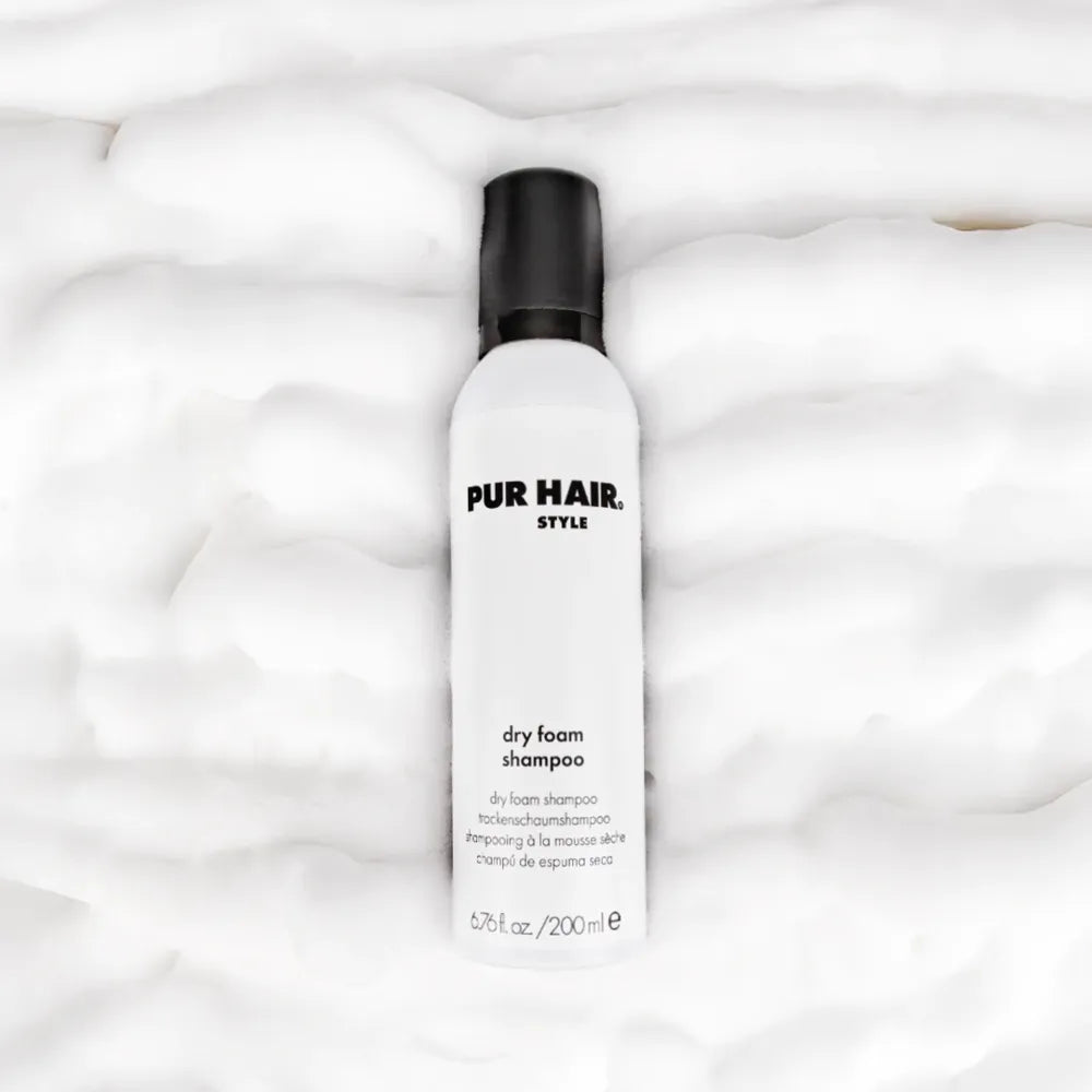 PUR HAIR Style Dry Foam Shampoo – weiße Flasche mit schwarzem Deckel, liegend auf fluffigem Schaum-Hintergrund, für frisches Haar ohne Waschen